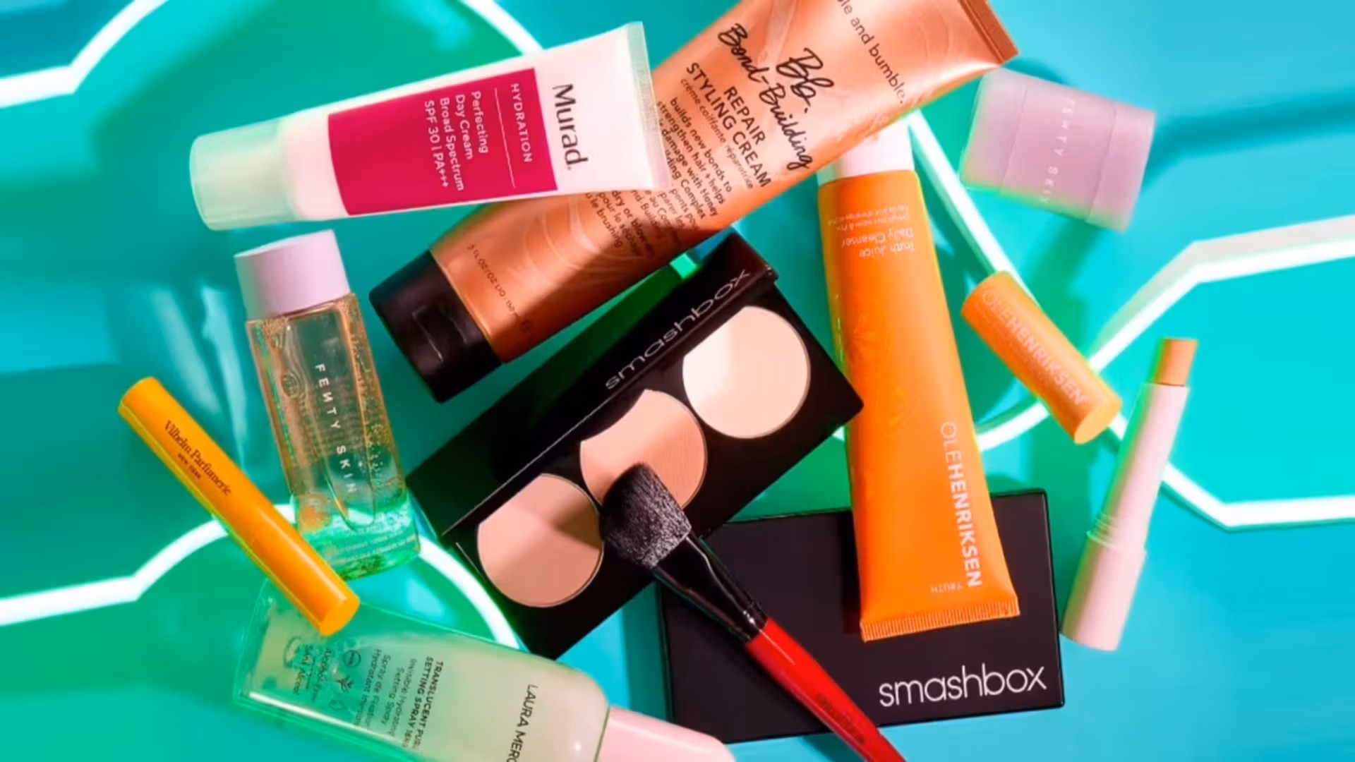 Skincare and makeup products from various brands scattered on blue background