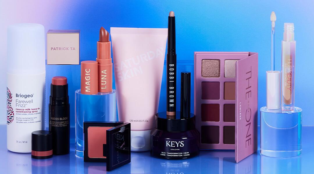Beauty products from various brands on gradient pink and blue background