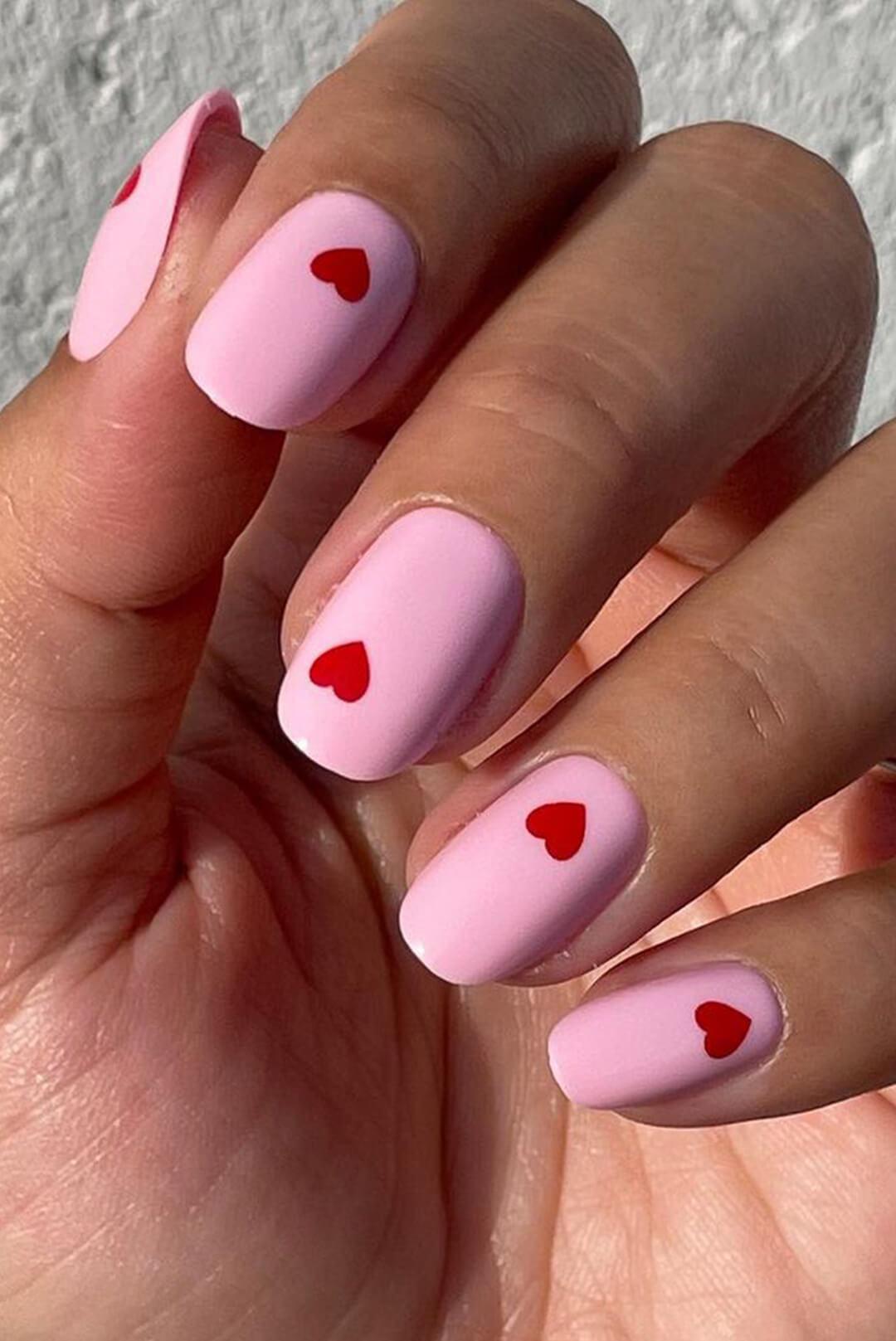 Close-up of a woman's pink nail polish with red heart nail art