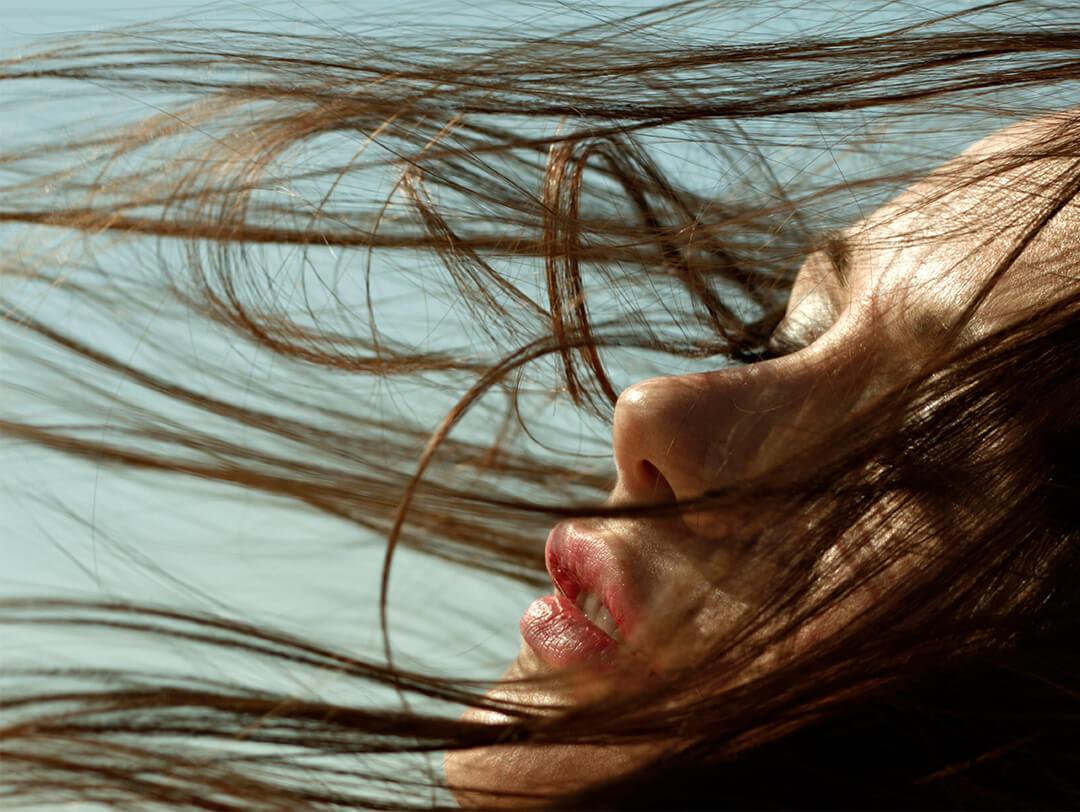 Close-up image of woman with hair blowing in wind