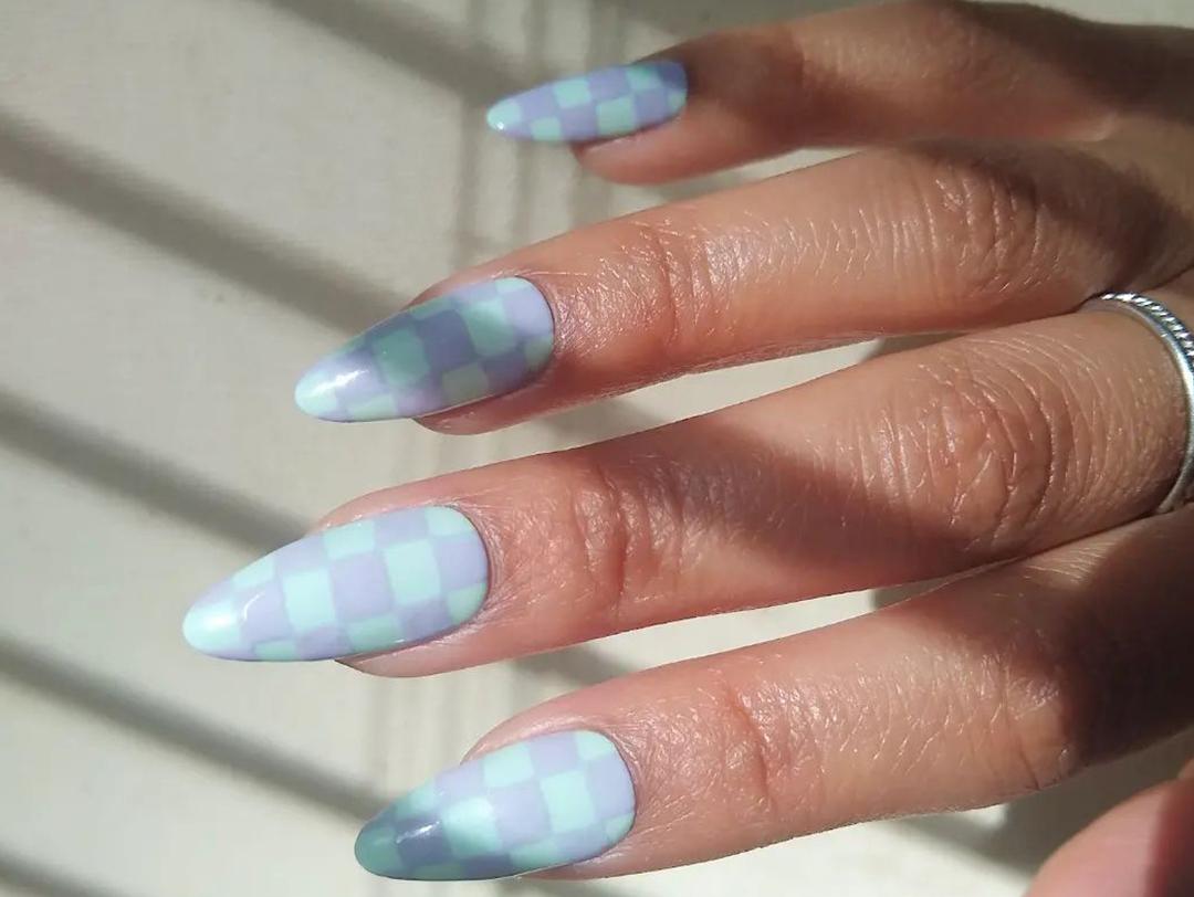 A photo of a model's hand with pastel colored almond shaped nails